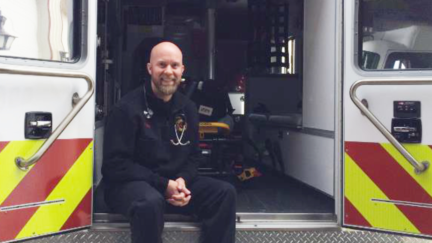 man in uniform setting inside the back of an ambulance