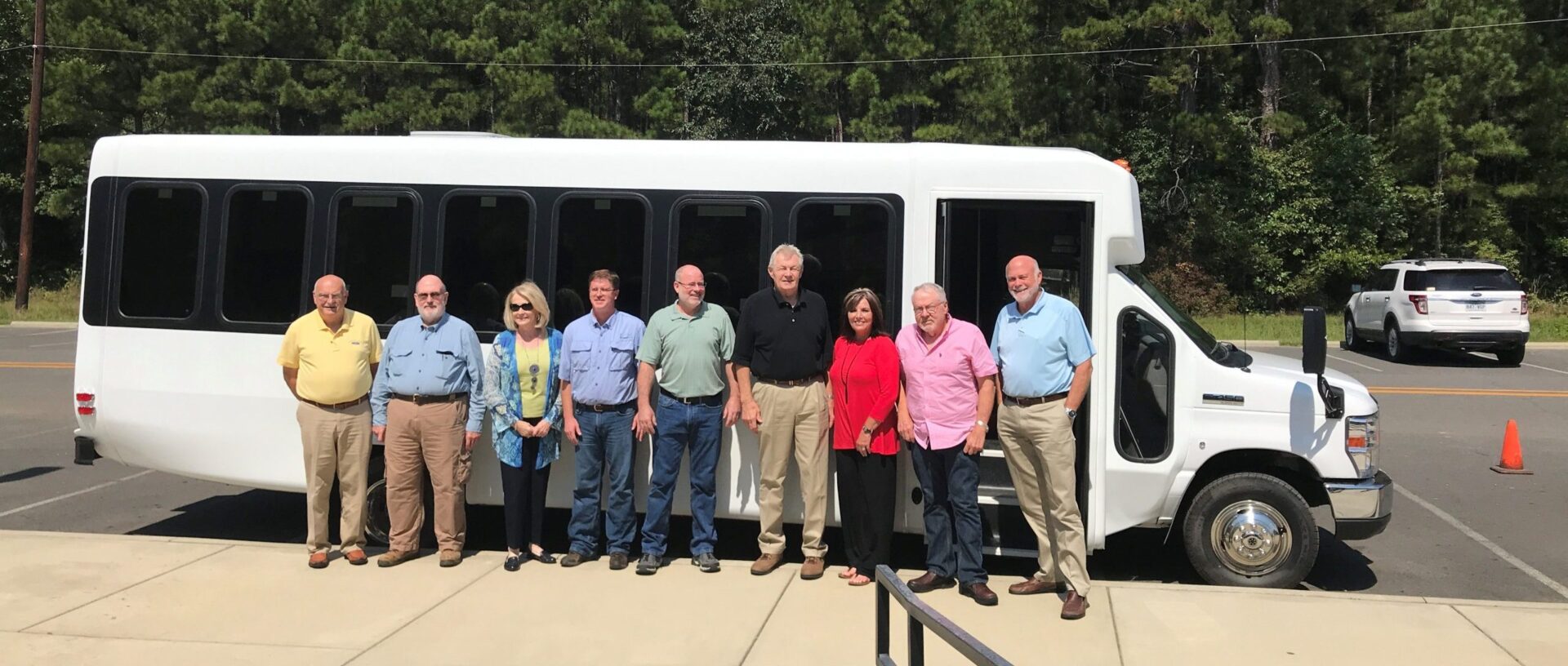 group of people posed by a passenger bus