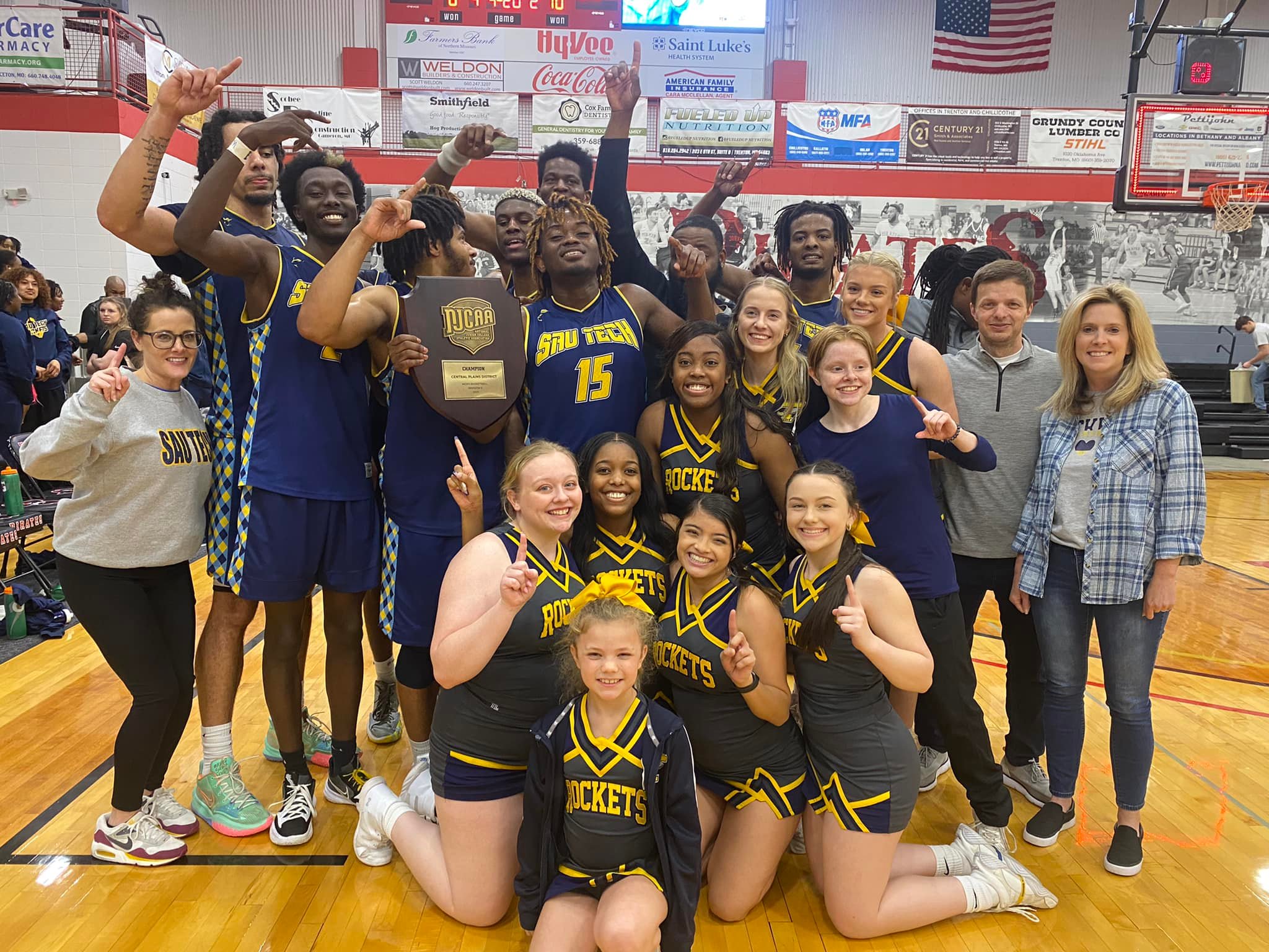 group of college basketball players. coaches and cheerleaders celebrating win