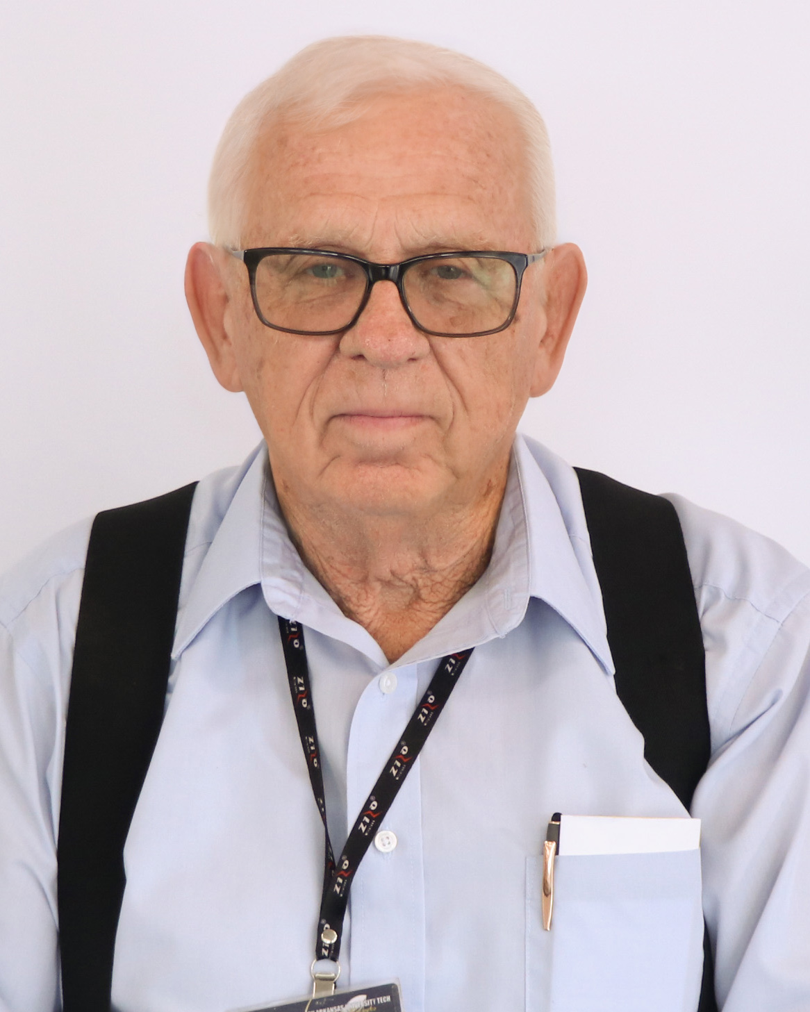 man with white hair wearing a blue shirt and glasses