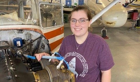 young woman working on a plane motor